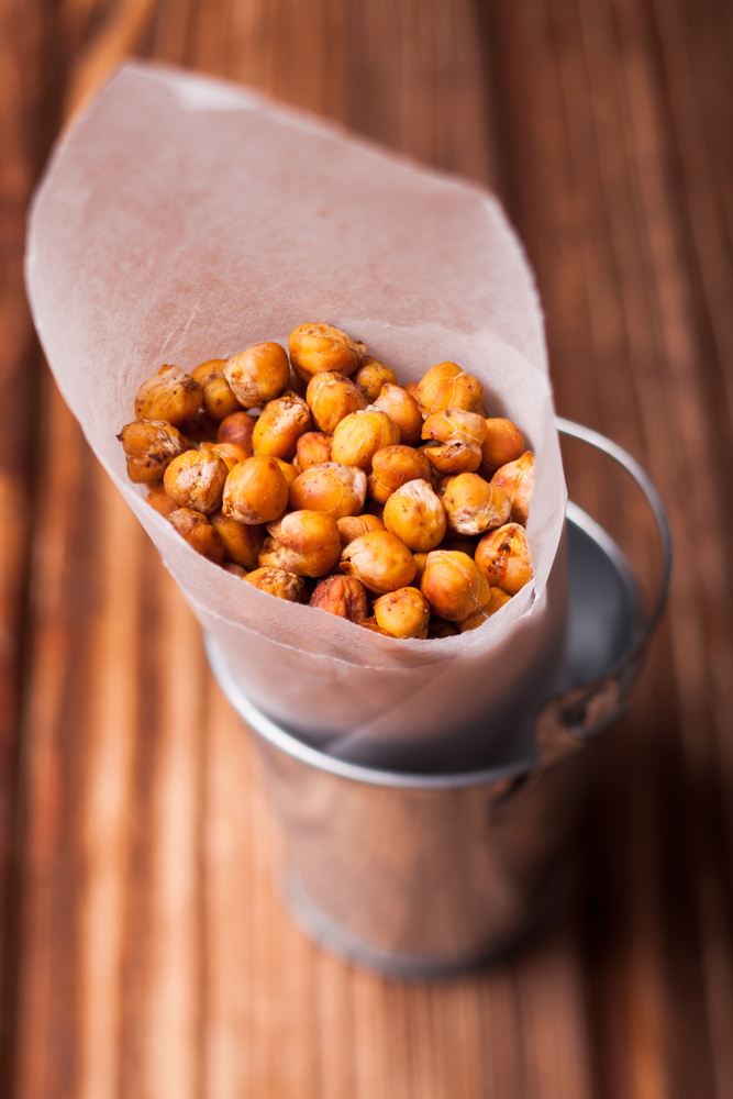Spicy baked chickpeas in a metal pail on the wooden background