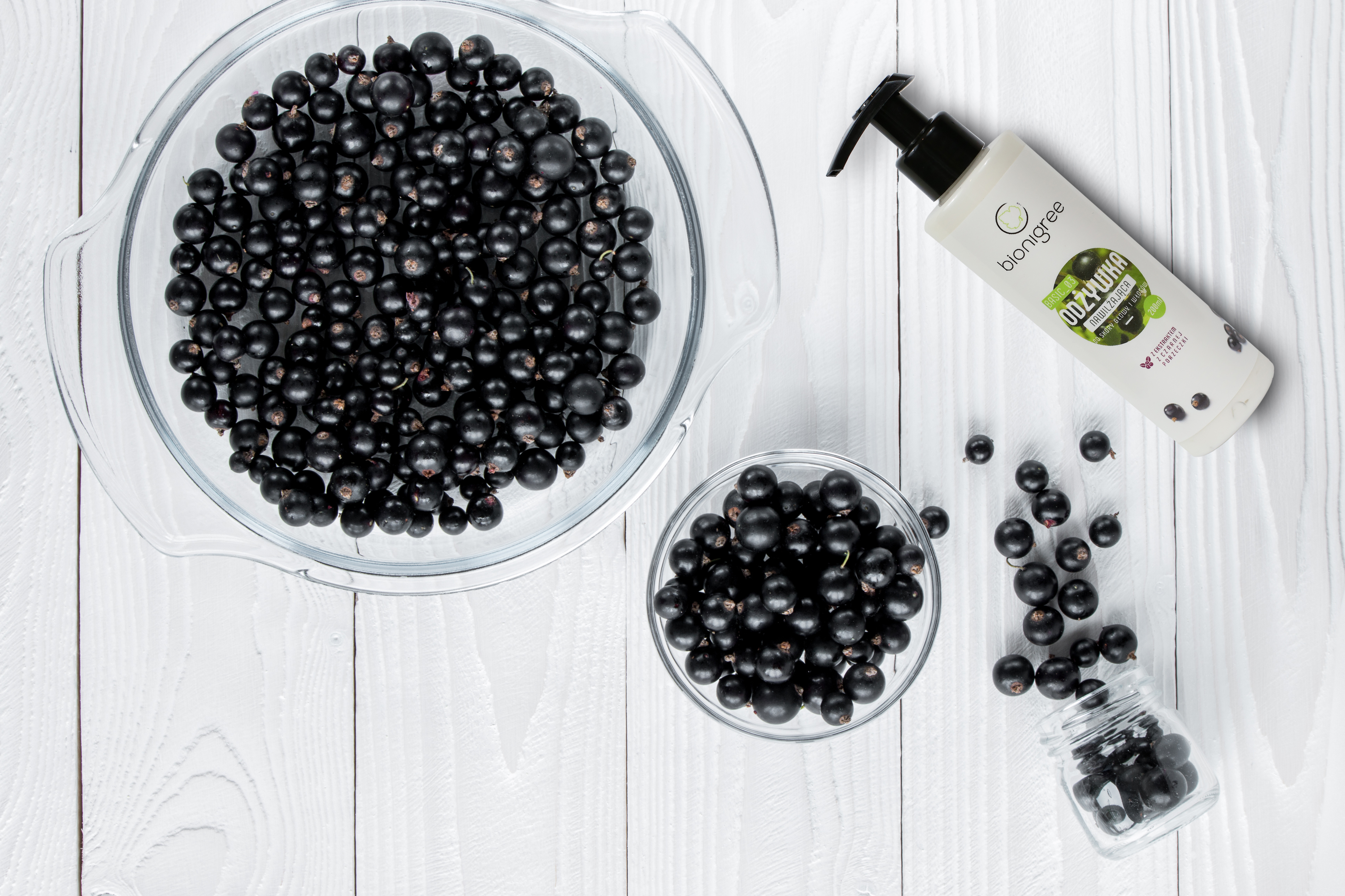 black currant in glassware on white wooden table  top view